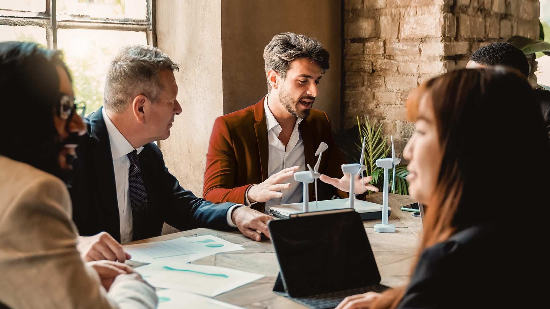 Employees talk about models of wind turbines in a meeting