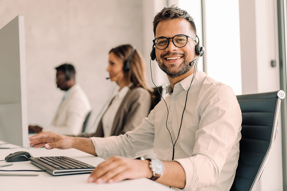 Mitarbeiter mit Headset schaut in die Kamera