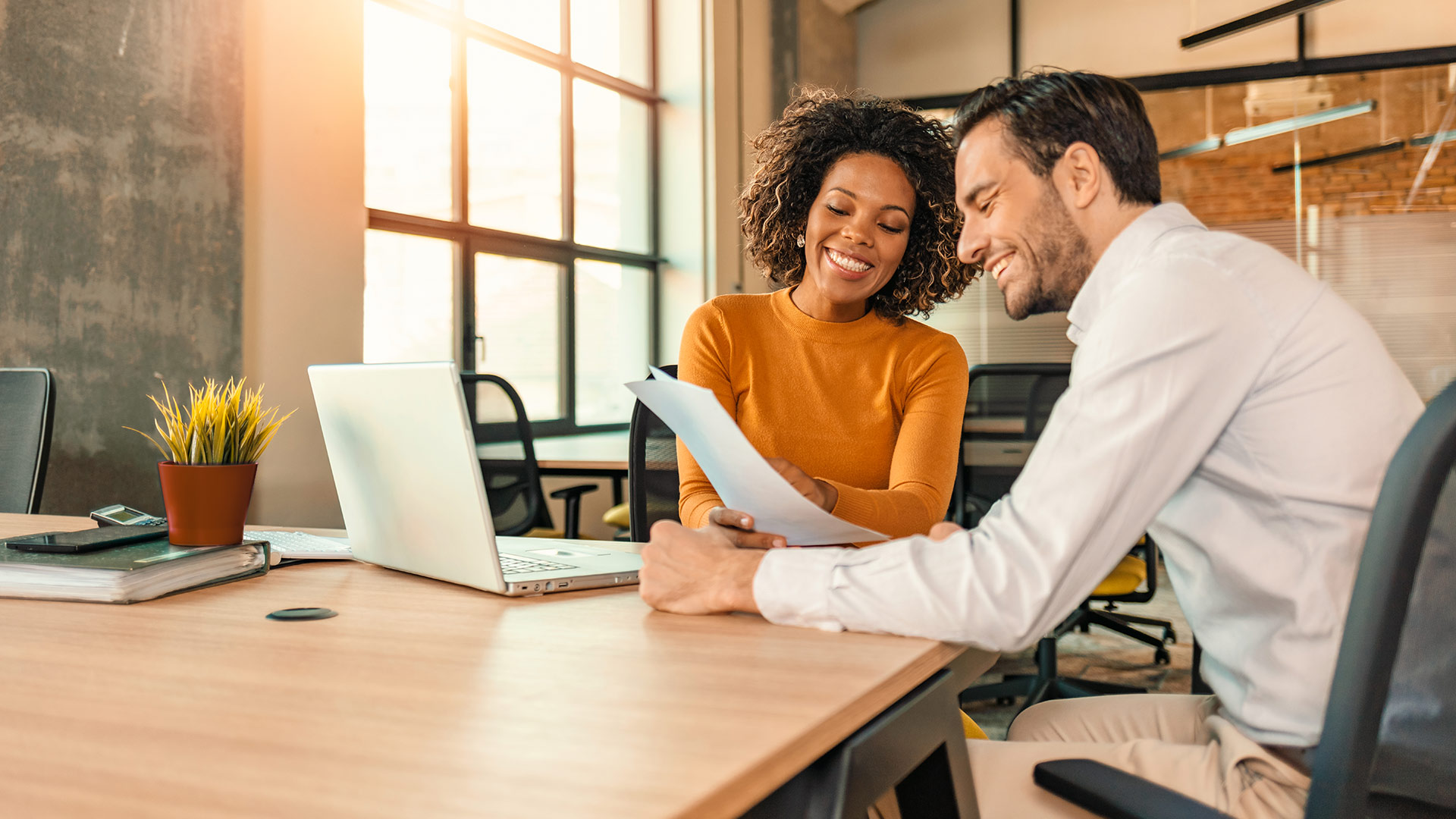 A woman and man discuss a printout in a meeting room